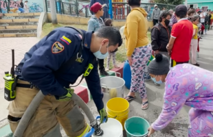 Bombero ayudando a la comunidad llenado baldes de agua