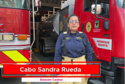 Bombera en medio de dos camiones de bomberos 